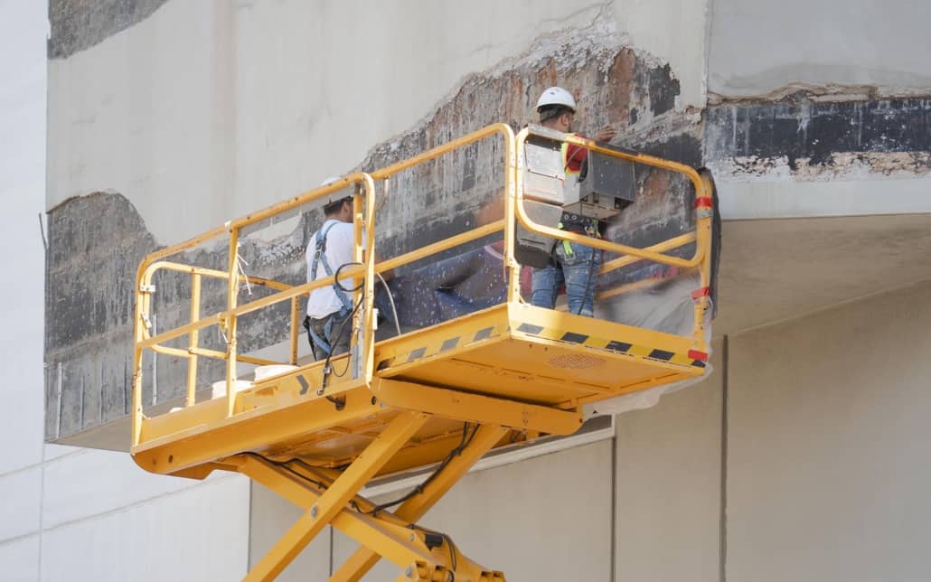 Two workers on lift fixing exterior of building