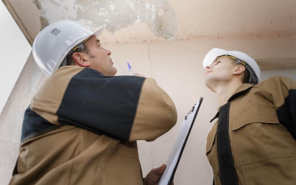 Two workers looking at wet ceiling
